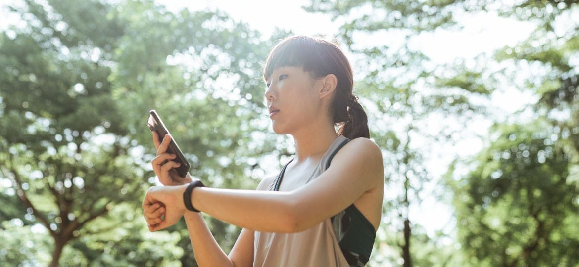 Woman using her smartphone to connect to her wearable device.